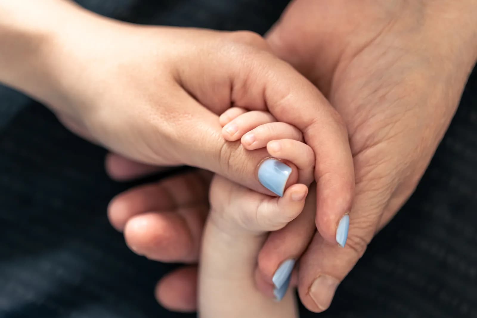 Mãos de adulto e de bebê entrelaçadas